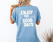 Load image into Gallery viewer, Blue garment-dyed coastal graphic t-shirt with “Enjoy the Good Days” back print, styled for a relaxed summer outfit

